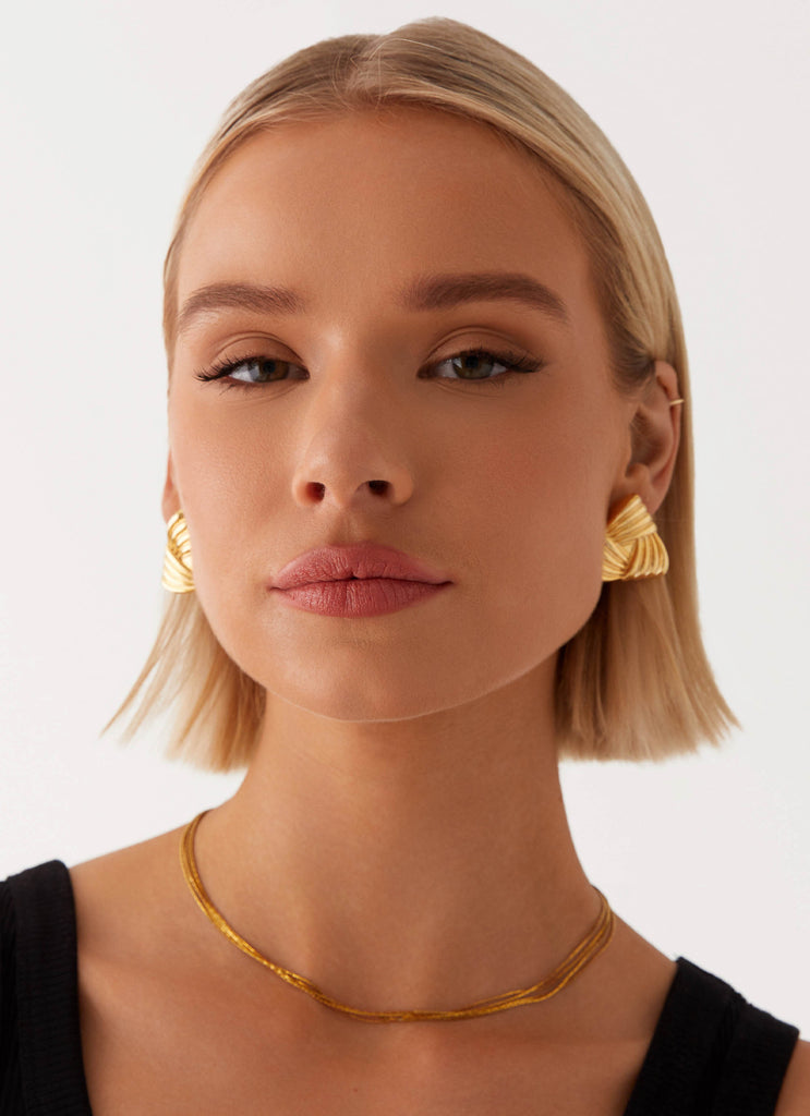 Womens Unholy Earrings in the colour Gold in front of a light grey background